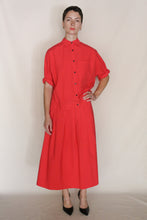 Load image into Gallery viewer, A person stands against a plain background wearing the Work Shirt Crop in Organic Typewriter Cotton Vermillion with rolled sleeves, paired with a matching red midi skirt, short hair, earrings, and black pointed heels. Handmade in San Francisco.