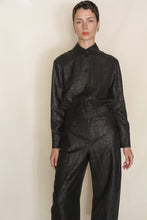 Load image into Gallery viewer, A person with short hair wears a shiny black Studio Shirt | Xiang Yun Silk Earth Mark and matching wide-leg pants, standing against a plain light background.