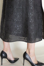 Load image into Gallery viewer, A person wearing the Reversible Futo Skirt in Xiang Yun Silk Endless Bloom, featuring subtle dark jacquard patterns, paired with black high-heeled shoes, shown from the calves down against a light background.