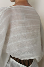 Load image into Gallery viewer, A close-up of a person wearing the Origami | Silk Double Cloth Woven Veil over a brown garment, with its sheer, textured fabric softly draping over their shoulders and upper back and subtly revealing the clothing underneath.