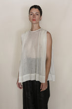 Load image into Gallery viewer, A person with short dark hair wears the Shoulder Pleat Top | Linen Leno Ivory, sleeveless and sheer, paired with loose black pants, standing against a plain light background and looking directly at the camera with a neutral expression.