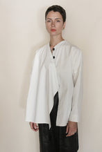 Load image into Gallery viewer, A person with short dark hair stands against a plain background, wearing the Qipao Blouse | Cotton Omizarashi Undyed over a dark garment, looking directly at the camera with a neutral expression.