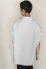 Load image into Gallery viewer, A person with short dark hair faces away, wearing the Men's Shirt | Cotton Omizarashi Undyed with rolled sleeves and black pants against a plain light background. Handmade in San Francisco.