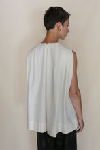 Load image into Gallery viewer, A person with short dark hair and a gold hoop earring stands facing away, showcasing the back of the Shoulder Pleat Top | Omizarashi Undyed against a plain light background.
