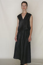 Load image into Gallery viewer, A person with short hair stands against a plain light background, wearing a sleeveless black V-neck top and the A Line Skirt | Xiang Yun Silk Faux Bois. They have a neutral expression with their arms resting by their sides.