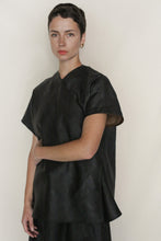 Load image into Gallery viewer, A person with short dark hair wears a loose-fitting, black Qipao Vest Reversible | Xiang Yun Silk Faux Bois and gold hoop earrings, standing against a plain light background with a neutral expression.