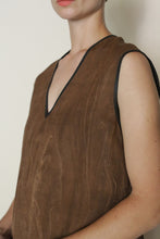 Load image into Gallery viewer, A person wears the V Neck Tank Reversible in Xiang Yun Silk Faux Bois—a sleeveless brown jacquard top with a V-neck and black trim—standing against a light background. Photo is cropped to upper body and part of face with neutral expression.