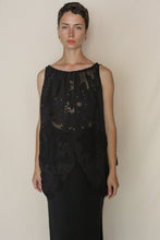 Load image into Gallery viewer, A person with short hair stands against a plain background, wearing the Butterfly| Silk Uragiri Black sleeveless sheer top over a long black skirt. They look directly at the camera with a neutral expression.