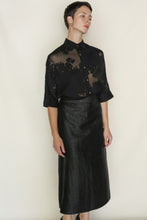 Load image into Gallery viewer, A person with short hair and a neutral expression stands against a plain background, wearing the limited edition Work Shirt | Silk Uragiri Black paired with a black high-waisted, shin-length skirt, capturing Lan Jaenicke’s modern minimalist style.