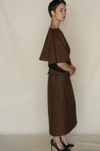 Load image into Gallery viewer, A person with short hair stands sideways, wearing the Kimono Top Reversible in Xiang Yun Silk Endless Bloom with loose sleeves and black trim, styled with black heels, against a plain light background.
