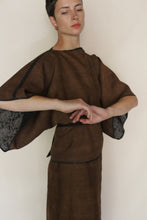 Load image into Gallery viewer, Woman wearing the Kimono Top Reversible | Xiang Yun Silk Endless Bloom, featuring wide patterned sleeves, stands against a plain background with arms elegantly in front of her and a serene expression, gazing slightly downward.