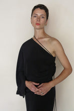 Load image into Gallery viewer, A person with short brown hair wears the Eurie Blouse in 2 Ply Silk Crepe Black and simple earrings, standing against a plain light background while gazing slightly past the camera.