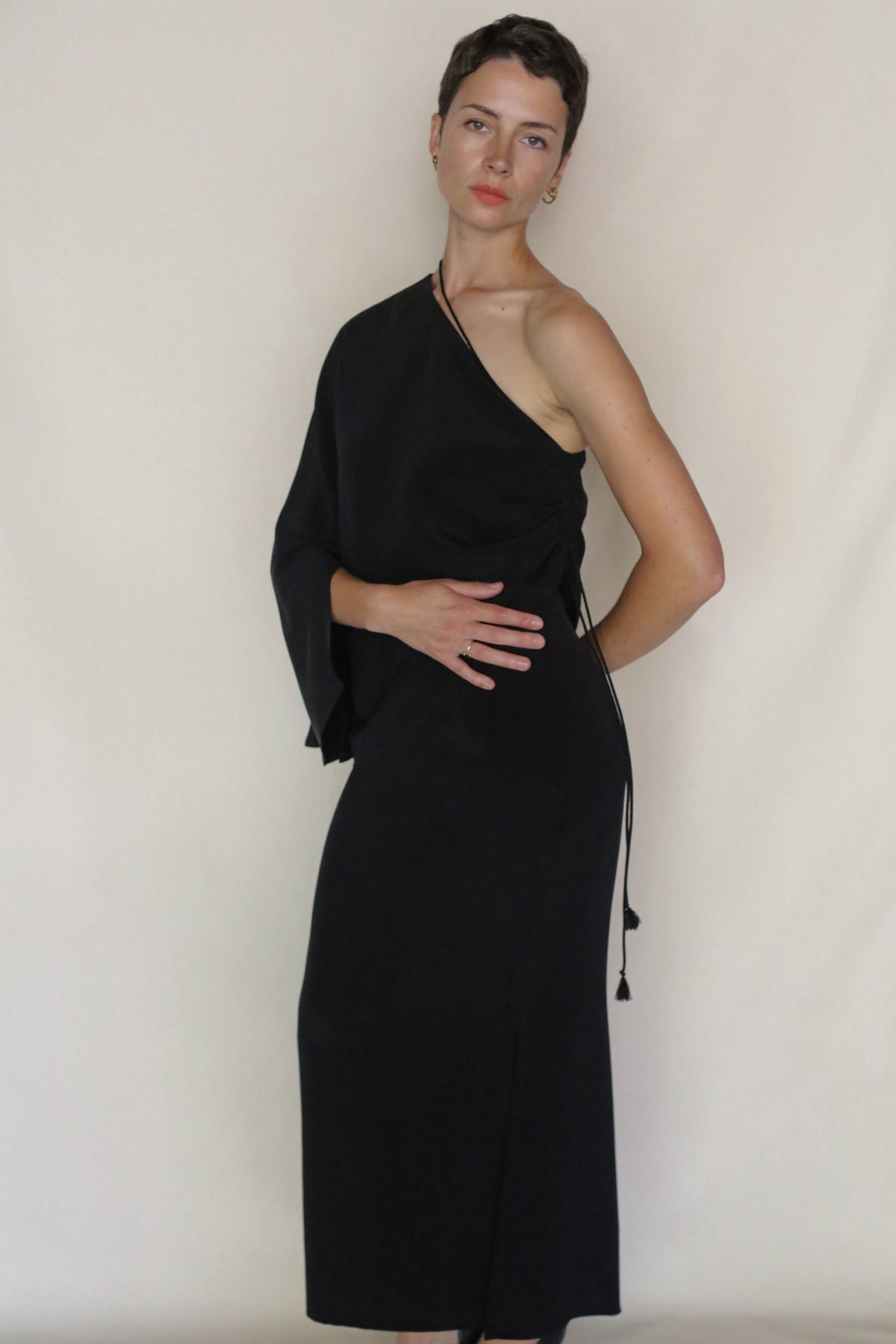 A person with short hair models the Eurie Blouse against a plain light background, posing with one hand on their waist and the other on their hip.