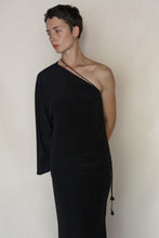 Load image into Gallery viewer, A person with short dark hair wears the Eurie Blouse in 2 Ply Silk Crepe Black, featuring an asymmetrical design with one long sleeve, and looks to the side against a plain, light background.