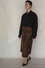 Load image into Gallery viewer, A person with short hair wears a loose black button-up shirt, the Reversible Futo Skirt | Xiang Yun Silk Lingering Fragrance, and black pointed-toe heels, standing against a plain light background.