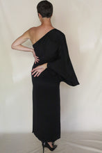 Load image into Gallery viewer, Wearing the Eurie Dress | 2 Ply Silk Crepe Black, a person stands with their back to the camera, one arm bent behind and the other on their hip, against a plain light background.