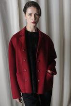 Load image into Gallery viewer, In front of a light curtain stands a person donning the Bamford Short Double-Face Cashmere coat in a wine hue, layered elegantly over a black top. Their short, neatly styled hair enhances the modern vibe of their ensemble as they gaze directly at the camera with an expressionless look.