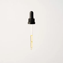 Load image into Gallery viewer, A transparent dropper featuring a black rubber top releases a single drop of vibrant yellow Phyto Radiance Day Oil against a light gray background.