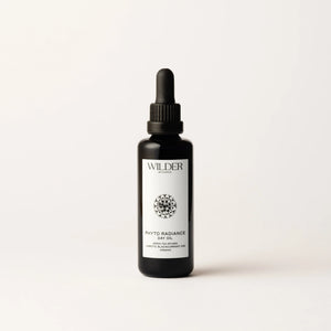 A small black dropper bottle labeled "Wilder Botanics" containing Phyto Radiance Day Oil, infused with Prickly Pear seed oil. The label features a geometric floral design and the bottle stands against a neutral background with soft shadows.