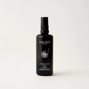 A sleek, black bottle of "Flower of the Sun Body Oil" with a convenient spray nozzle. The label boasts a delicate floral illustration and emphasizes the inclusion of 13 botanicals such as Calendula oil, which are designed to nourish and enhance skin hydration. The bottle is photographed against a simple white background.