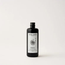 Load image into Gallery viewer, A black bottle with a metallic screw cap boasts a minimalist label design. &quot;Wilder Botanicals&quot; is written at the top of the label, with &quot;Immortelle Cleansing Oil&quot; at the bottom. The central part of the label showcases a floral illustration, accentuating its blend of skin-renewing botanicals such as organic Manuka. The background is plain white.