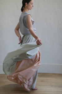 A woman in a Silk Reversible Pleated Long Wrap Skirt | Celadon/Blush.