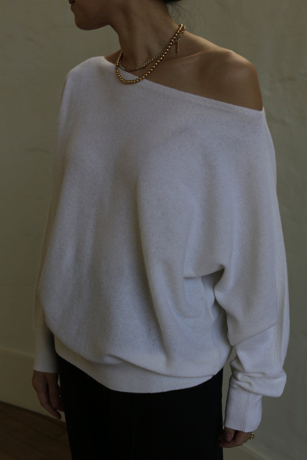 A woman wearing a relaxed fit, Ballerina's Cashmere Sweater | Ivory with a boat neck.