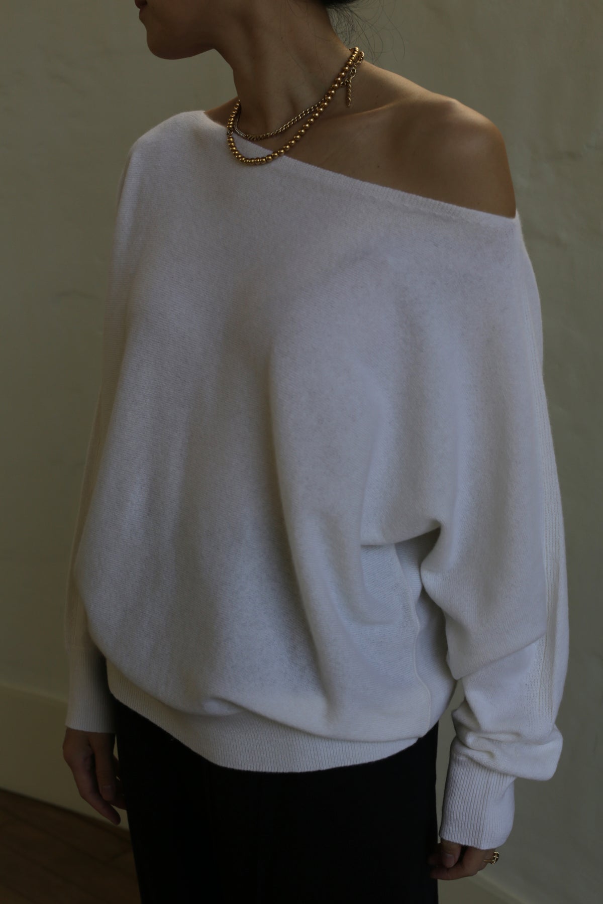 A woman wearing a relaxed fit, Ballerina's Cashmere Sweater | Ivory with a boat neck.